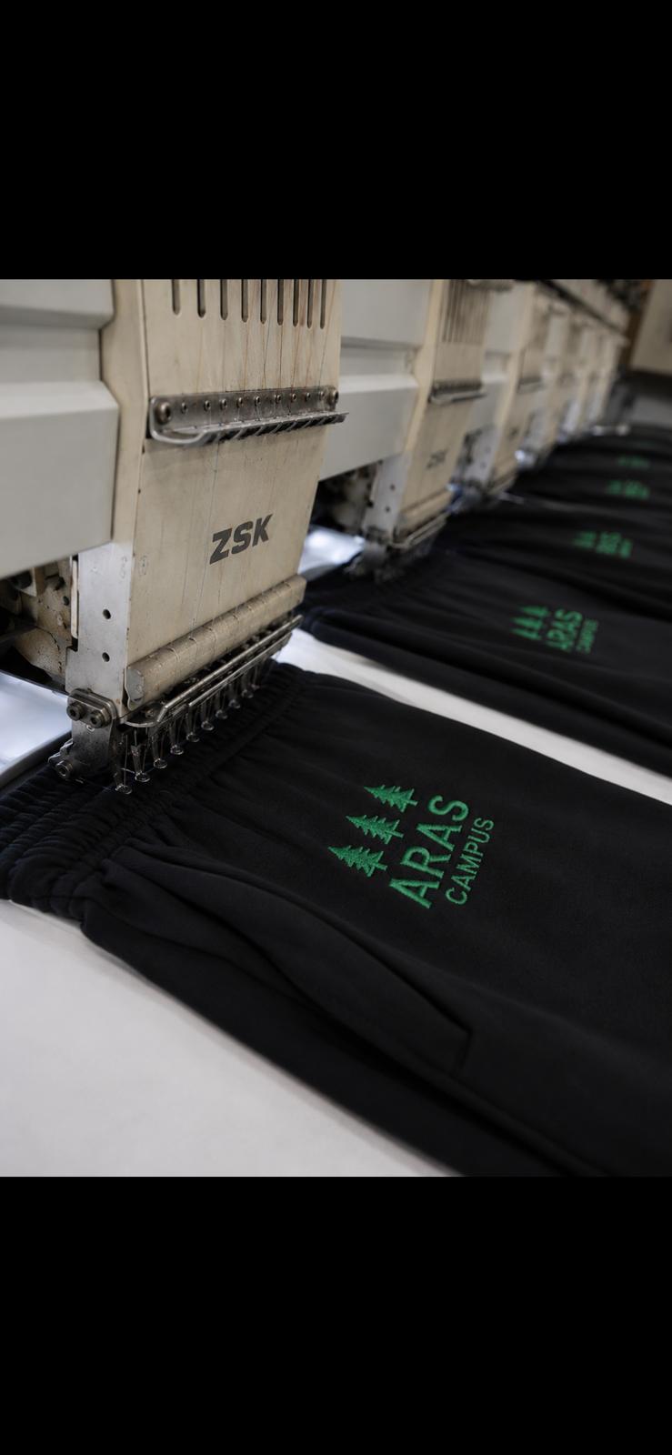 Embroidered in-house — every garment finished with care on hand-tuned ZSK machines.