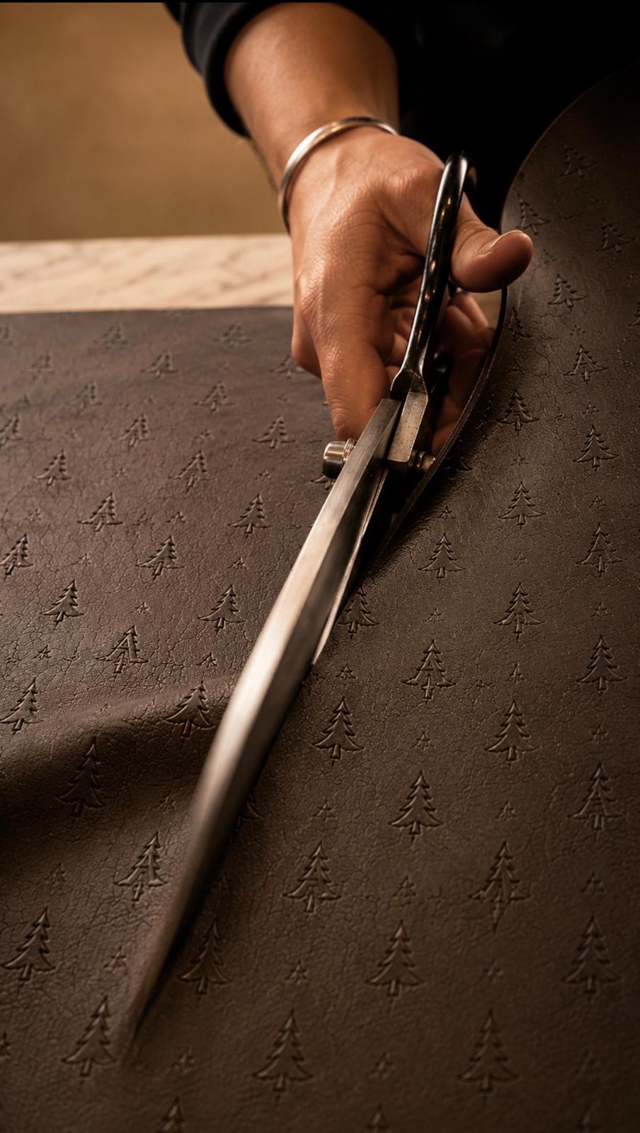 Craftsperson cutting brown leather embossed with the ARAS pine emblem